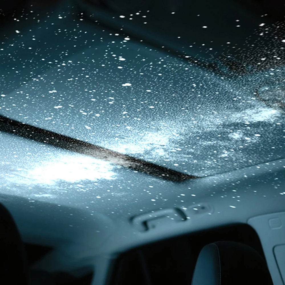 Interior de un coche con el techo iluminado por el proyector Lovuris Nova creando un efecto de cielo estrellado y galaxia azul.